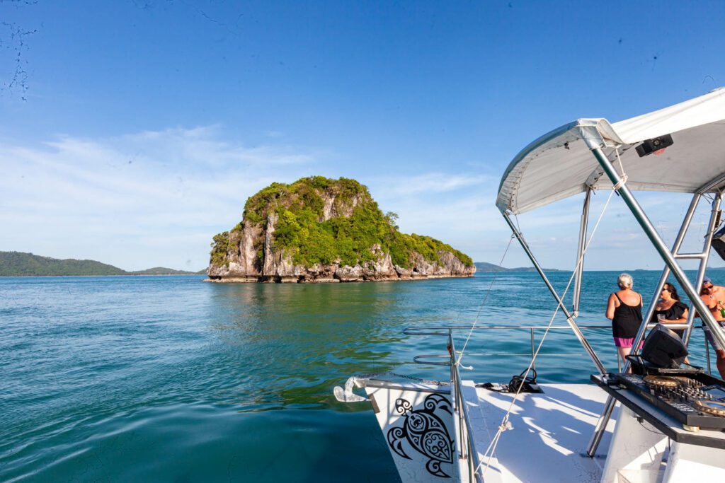 People spectating an island in the Thai Gulf off the side of a power catamaran